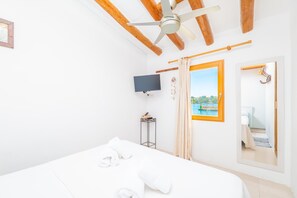 Une chambre d’hôtel avec un lit, un ventilateur de plafond, une télévision, une fenêtre donnant sur une piscine et un miroir.