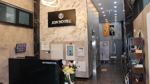 A hotel reception area with a marble wall, a sign reading "ION HOTEL", an information desk, and a staircase leading to an elevator. - ION HOTEL DONGDAEMOON (Seoul)