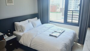 A hotel room with a large bed, a bedside table with a phone and tissues, a chair, and a window with curtains. - ION HOTEL DONGDAEMOON (Seoul)