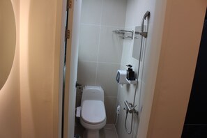 A small bathroom with a toilet, a shower, and a soap dispenser on the wall. - ION HOTEL DONGDAEMOON (Seoul)