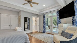 A bedroom with a bed, a chair, a television, and a view of the outdoors. - Tybee Skies: 4 BDR 4 Bath Oceanfront Home w Pool (Tybee Island)