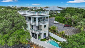 A multi-story building with a pool, surrounded by lush greenery and a clear view of the ocean. - Tybee Skies: 4 BDR 4 Bath Oceanfront Home w Pool (Tybee Island)