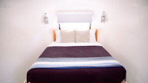 Ein Bett mit Holzrahmen, weißen und beigen Kissen und einer gestreiften Decke.