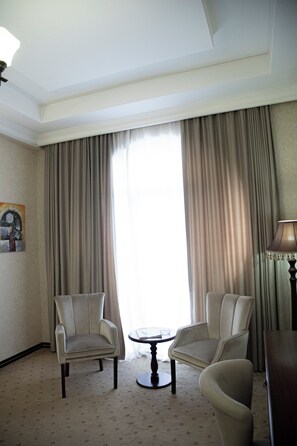 A hotel room with two armchairs, a small round table, and a lamp. - Capitol Hotel (Baku)