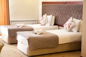 A hotel room with two beds, each with a duvet, pillows, and a rolled towel. - Capitol Hotel (Baku)