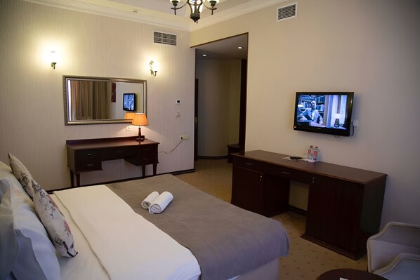 Una habitación de hotel con cama, escritorio, televisor y espejo.