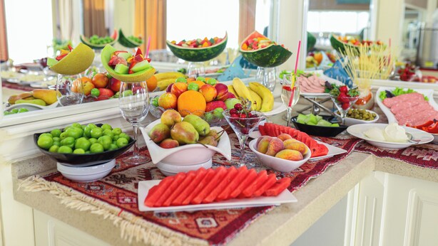 A buffet table with various fruits, vegetables, and meats.