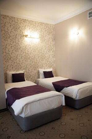 A hotel room with two beds, patterned wallpaper, and wall-mounted lights. - Capitol Hotel (Baku)