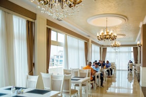 A spacious dining area with chandeliers, large windows, and a modern interior design. - Capitol Hotel (Baku)