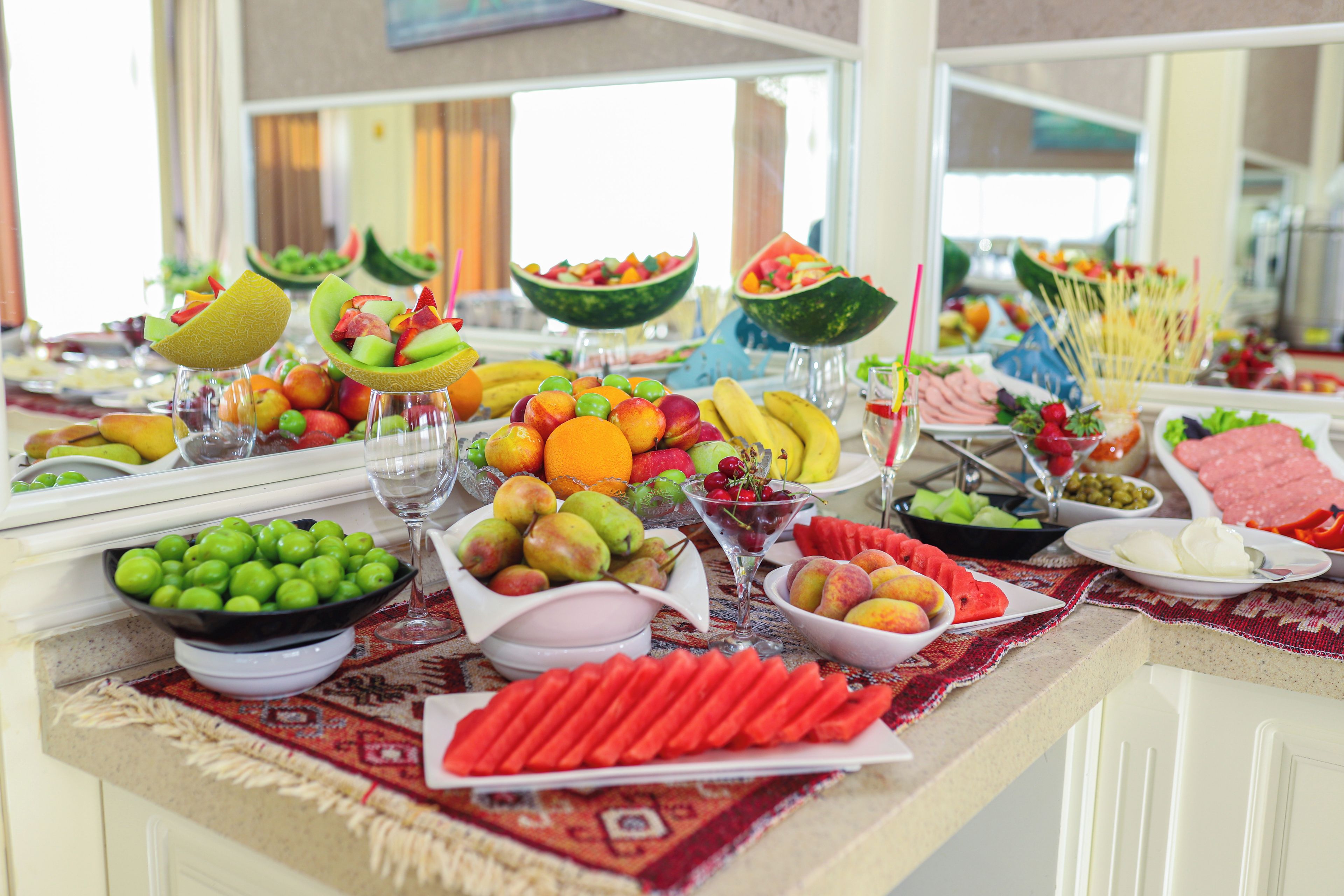 A buffet table with various fruits, vegetables, and meats.