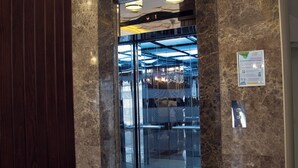 An elevator entrance with marble walls and hanging light fixtures.