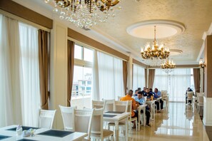 A spacious dining area with high ceilings, chandeliers, and large windows. - Capitol Hotel (Baku)