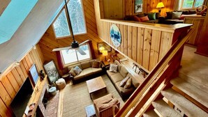 A cozy cabin interior with a loft bedroom, a living area with a sofa and coffee table, and a dining area. - Chalet at Mt Snow, ski-home, free shuttle (Dover)