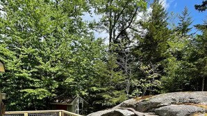 A wooden deck with wicker furniture and a view of a rocky landscape. - Chalet at Mt Snow, ski-home, free shuttle (Dover)