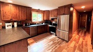A kitchen with wooden cabinets, stainless steel appliances, and a large window. - Chalet at Mt Snow, ski-home, free shuttle (Dover)
