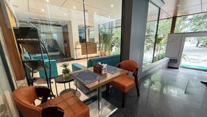 Un interior moderno con mostrador de recepción, zona de estar y amplios ventanales que ofrecen vistas al exterior.
