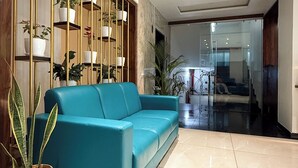 Un salón moderno con un sofá color aguamarina, una estantería de madera para plantas y una planta grande en maceta.