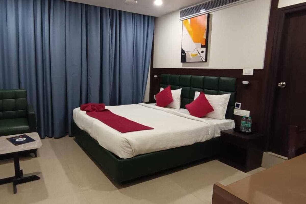 Una habitación de hotel con cama, escritorio, silla, televisor y puerta.