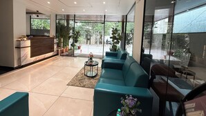 Un vestíbulo moderno con mostrador de recepción, zona de estar y amplios ventanales con vistas al exterior.
