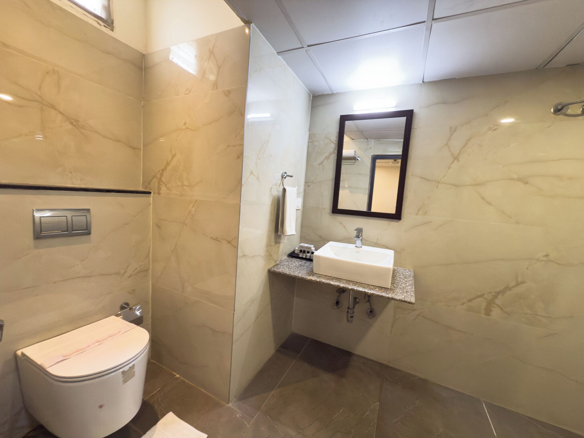 A bathroom with a toilet, sink, mirror, and tiled walls.