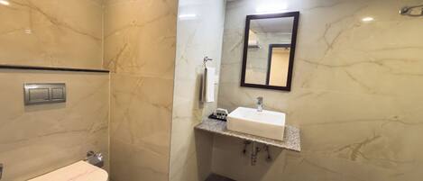 A bathroom with a toilet, sink, mirror, and tiled walls.