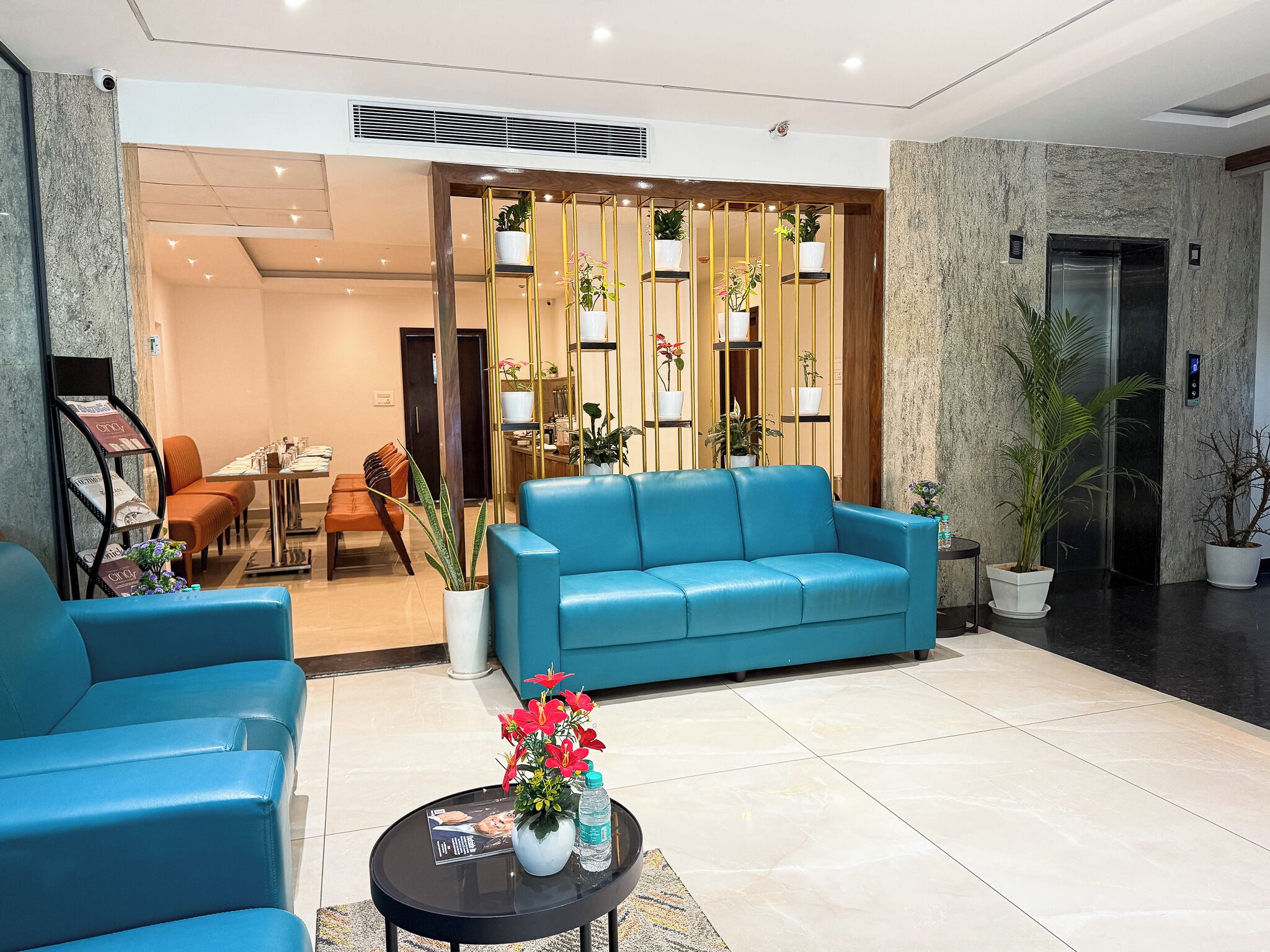 A modern lobby with a blue sofa, a coffee table with flowers, and a reception desk.