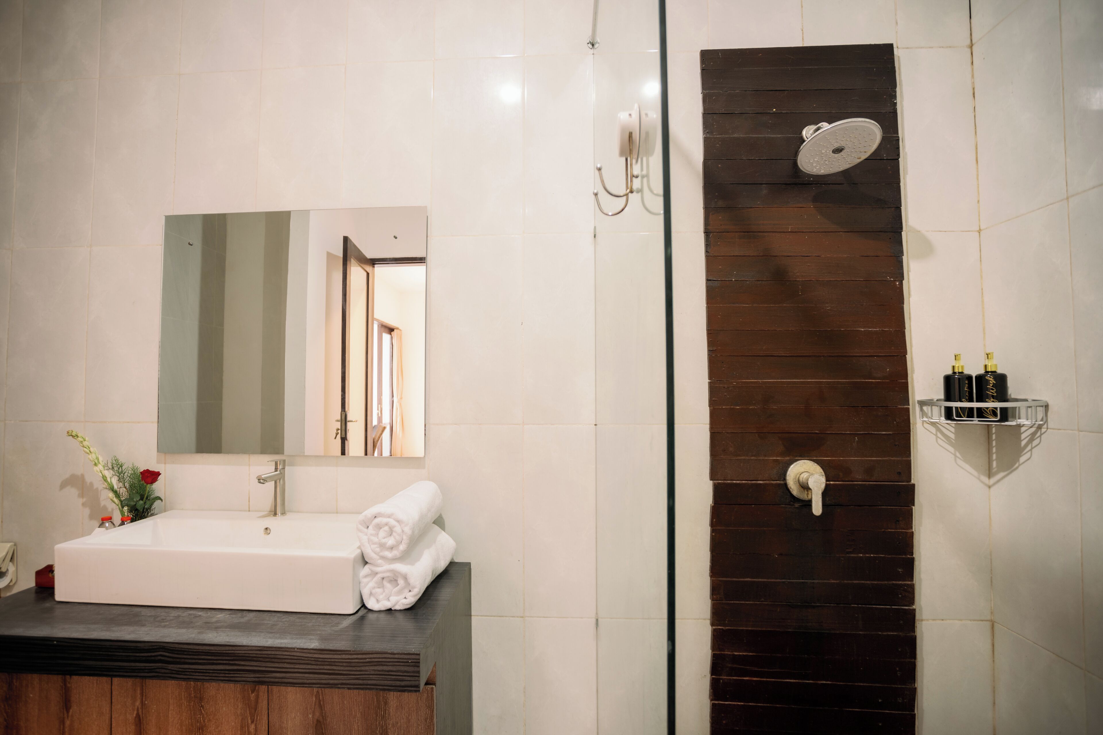 Een badkamer met een witte wastafel, spiegel en douche.