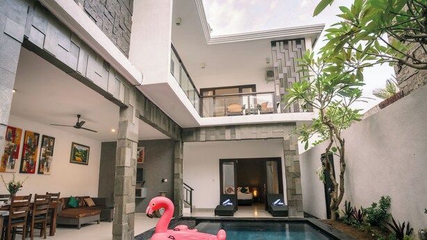 A modern house with a swimming pool, a dining area, and a living room with a sofa and chairs. - Taman Bali Villa Kerobokan (Kerobokan)