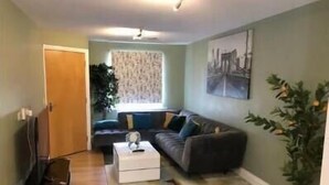 A living room with a sofa, a coffee table, and a potted plant. - 3 Bed House - Sleeps 6 - Garden - Parking (Bristol)
