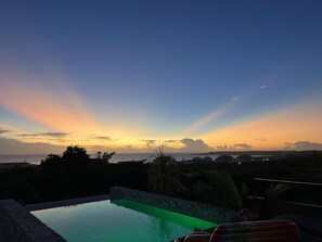 Ein Schwimmbecken mit Blick auf den Sonnenuntergang und die ferne Landschaft.