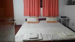 Ein Schlafzimmer mit Bett, Kissen, Nachttisch und einem Fenster mit Vorhängen.