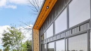 A modern building with large glass windows and a wooden deck.