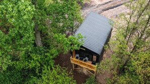 A wooden cabin with a metal roof surrounded by dense green foliage.