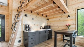 A modern kitchen with wooden walls, a built-in stove, and a dining area with a table and chairs.