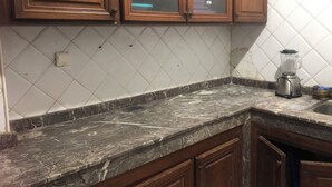 A kitchen with wooden cabinets, a marble countertop, and a blender on the counter. - Captivating 4-Bed House in Tamaris (Tamaris)