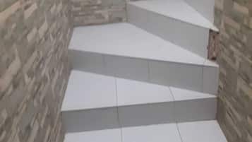 A set of white steps leading up to a landing area with a patterned wall.