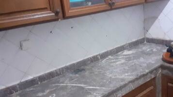 A kitchen with wooden cabinets, a marble countertop, and a tiled backsplash.