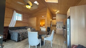 Un intérieur de chalet chaleureux comprenant un coin repas, une cuisine et un espace nuit.