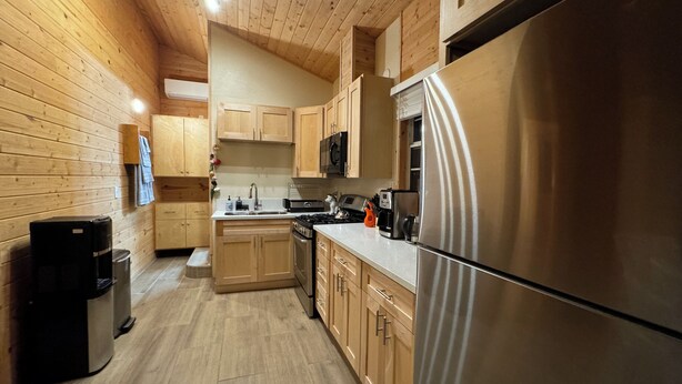 Une cuisine moderne avec des murs en bois, des appareils électroménagers en acier inoxydable et un îlot central.