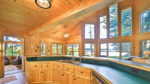 A spacious kitchen with wooden cabinets, a large island, and multiple windows offering views of the outdoors.