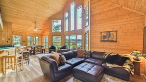 A spacious living area with a large L-shaped leather sofa, a dining table with chairs, and a kitchen area with a bar.