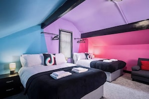 Une chambre avec deux lits, une fenêtre, une table de chevet et une chaise.