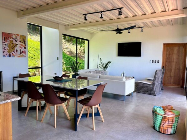 Una cocina moderna con comedor, ventanas amplias y un televisor montado en la pared.