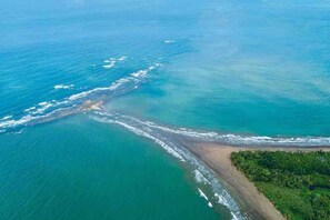 Vista aérea de una zona costera con playa, agua cristalina y vegetación densa.