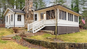A two-story house with a stone chimney, a covered porch, and a small attached garage. - Endearing Lakeside Private Retreat  (Hendersonville)