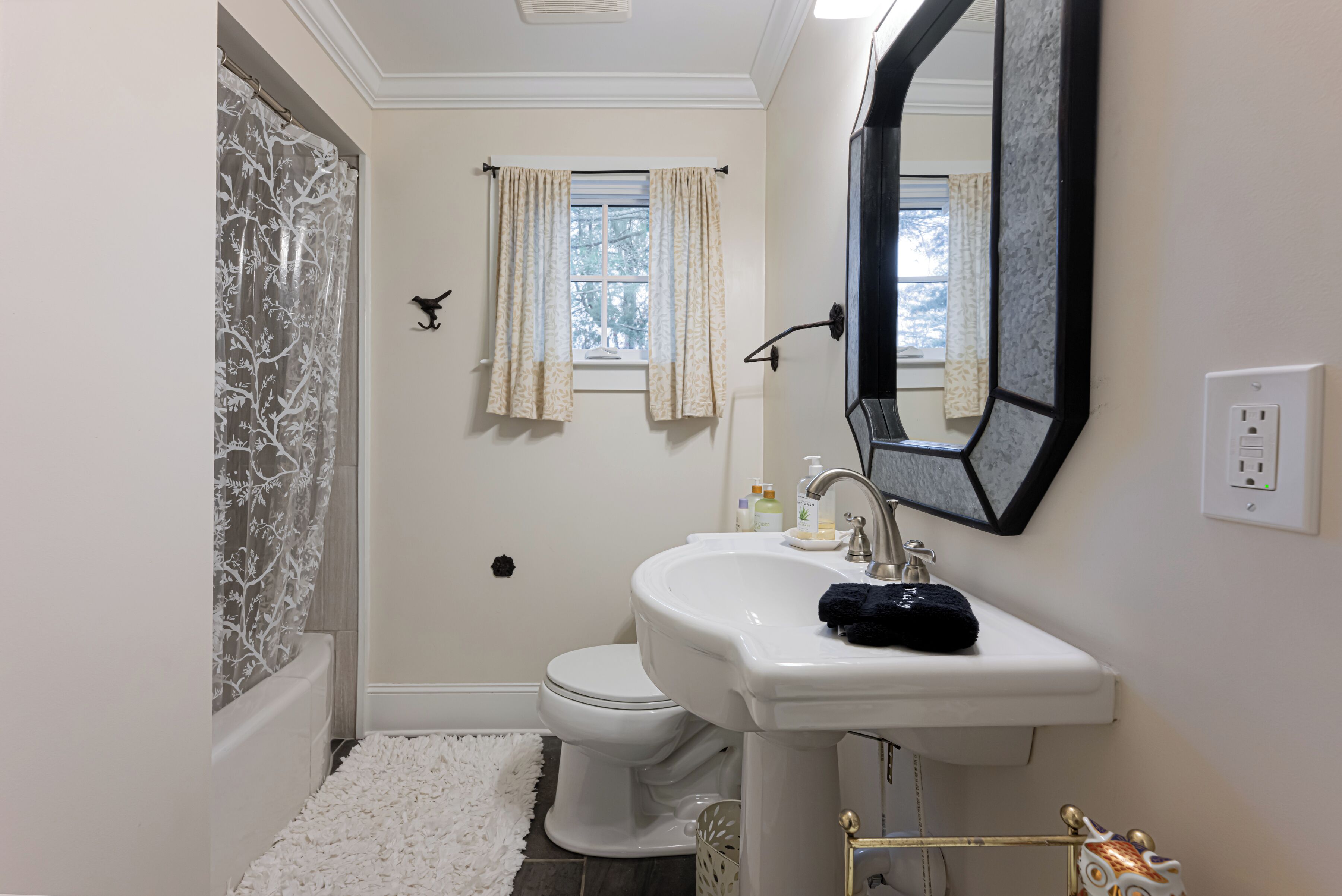 A bathroom with a white sink, a mirror, a toilet, and a shower curtain.