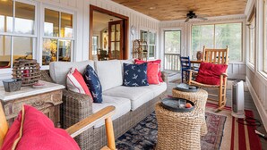 A cozy room with a wicker sofa, a wooden rocking chair, and a large window. - Endearing Lakeside Private Retreat  (Hendersonville)