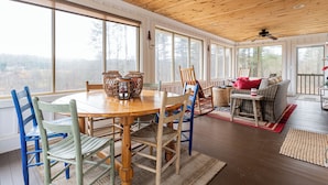 A spacious dining area with a wooden table and chairs, large windows offering a view of the outdoors, and a ceiling fan. - Endearing Lakeside Private Retreat  (Hendersonville)