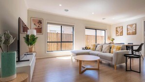A spacious living room with a sofa, coffee table, and a TV on a stand.