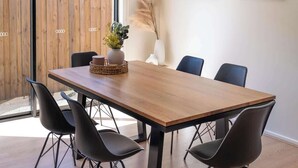 A dining area with a wooden table, black chairs, and two wall-mounted artworks.